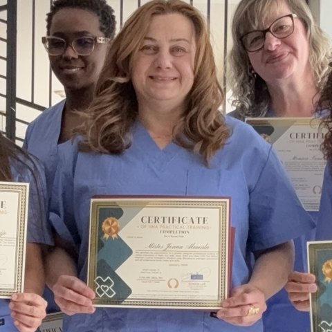 Aluna formada segurando o certificado de Home Health Aide da School LAR